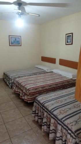 two beds are lined up in a room at Hotel Perseo Inn in Barranca