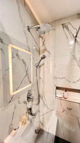 a shower in a bathroom with a marble wall at The Essence Studios, Accra Kotoka Airport in Accra