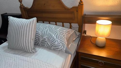 a bed with a lamp on a wooden table at Entire apartment centro ponferrada in Ponferrada