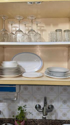 a kitchen shelf with plates and glasses and a sink at Entire apartment centro ponferrada in Ponferrada