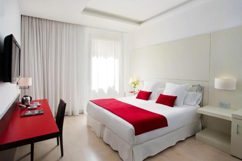 a bedroom with a large white bed and a red desk at Grupotel Gran Via 678 in Barcelona