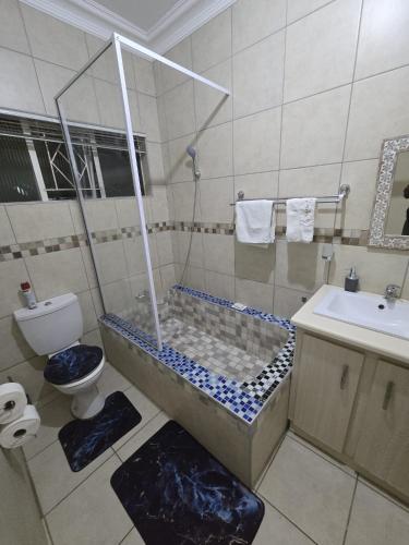 a bathroom with a shower and a toilet and a sink at Oasiselfcatering guest house in Vosburg