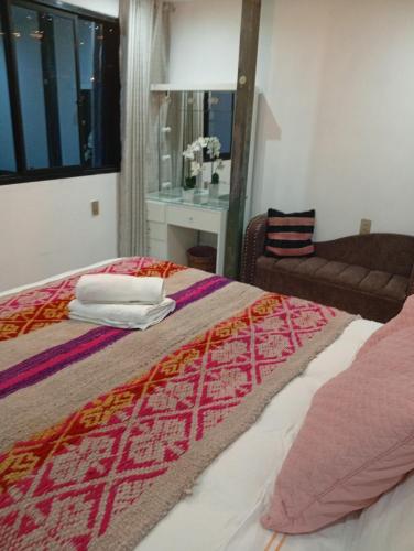 a bedroom with a bed and a chair and a window at Departamento con súper desayuno in Cusco