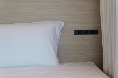 a bed with a white pillow in a room at GRAND HOSTEL LDK Tokyo Nishikasai -GRAND OPENING In May 2025- in Tokyo