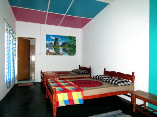 2 Betten in einem Zimmer mit farbenfroher Decke in der Unterkunft Achintha Family Guest House in Hatton
