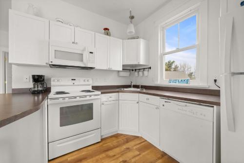 a white kitchen with white appliances and a window at The Willow - 20 Butternut in Cherry Valley