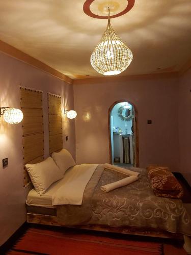 a bedroom with a large bed and a chandelier at DAR DANI café restaurant in Boumalne