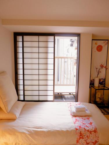 a bed in a room with a large window at Sannö Sakura House Japanese Entire House with 2 Bedrooms &Near Tennoji 7 min Walk &Near Public Transport Near Abeno Harukas &Direct to Namba Kansai Airport and USJ in Osaka