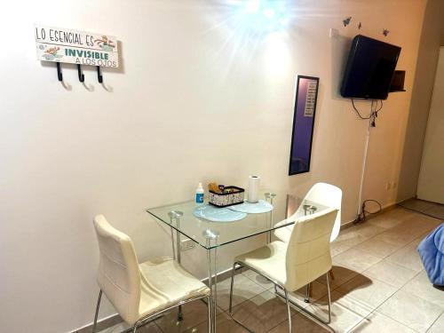 ein Esszimmer mit einem Glastisch und weißen Stühlen in der Unterkunft Monoambiente EK Centro Neuquén in Neuquén