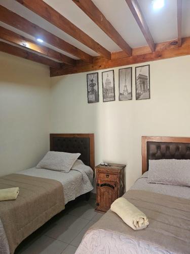 a bedroom with two beds and a wooden ceiling at Hostal Aires del Sur Renovado in Rancagua