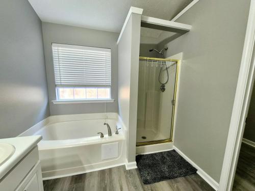 a bathroom with a tub and a shower and a sink at Cozy 5-Bedroom Home with Spacious Deck in Buford