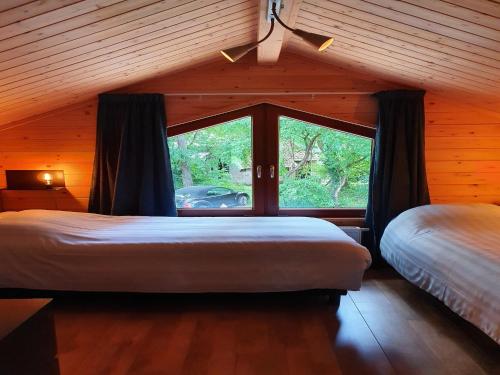 a bedroom with two beds and a large window at Villa in Forest with Private Sauna in Markelo