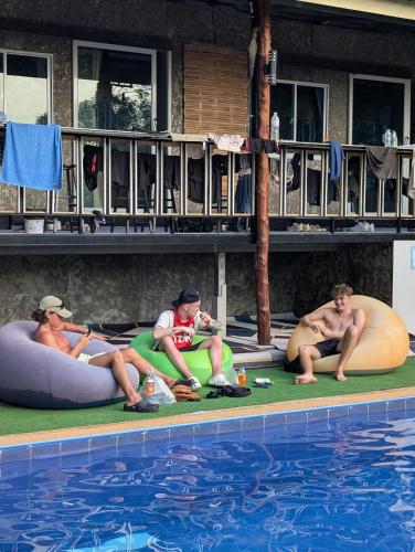 a group of people sitting on inflatablelatableainers near a swimming pool at Hangover Chill & Hill Hostel in Phi Phi Don