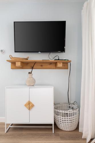 a flat screen tv on top of a white cabinet at Driftwood Dreams 1B in Traverse City