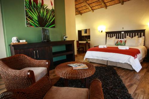 a bedroom with a bed and a living room at Woodlands Guest House in Hazyview