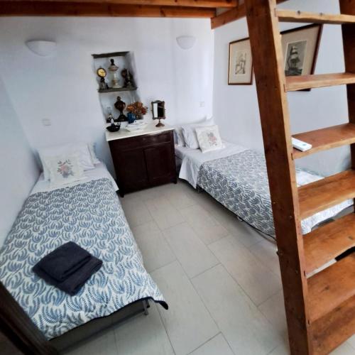two beds in a small room with a ladder at Traditional two floor house 75m2 in Andros