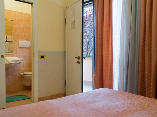 チャンピーノにあるHotel Louis IIのベッドのある寝室とトイレのある浴室