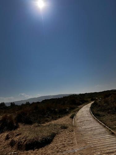 a dirt road leading to the beach with the sun in the sky at The Aurora van at Presthaven sands holiday park and beach resort in North Wales- 8 berth in Prestatyn