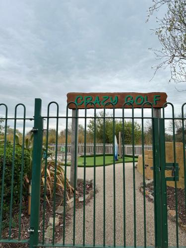 a gate at a park with a playground behind it at The Aurora van at Presthaven sands holiday park and beach resort in North Wales- 8 berth in Prestatyn