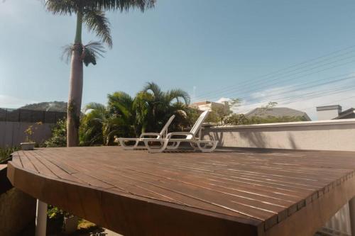 two white chairs on a wooden deck with a palm tree at Casa deslumbrante, com vista para o mar in Camboriú