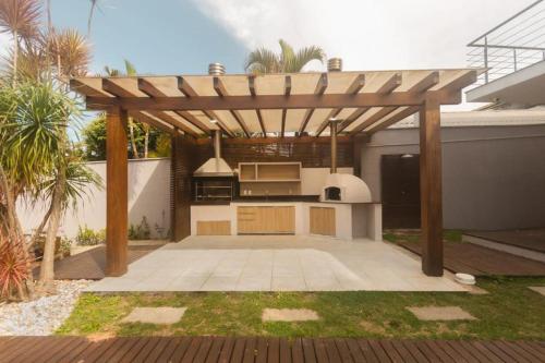a kitchen under a wooden pergola in a backyard at Casa deslumbrante, com vista para o mar in Camboriú