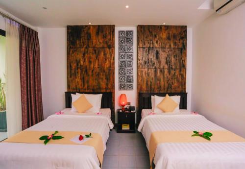 a bedroom with two beds with white sheets at Angkor Home 27 in Phumĭ Réach Born