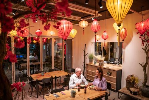 two people sitting at tables in a restaurant with red lanterns at Landal Travemünde in Travemünde