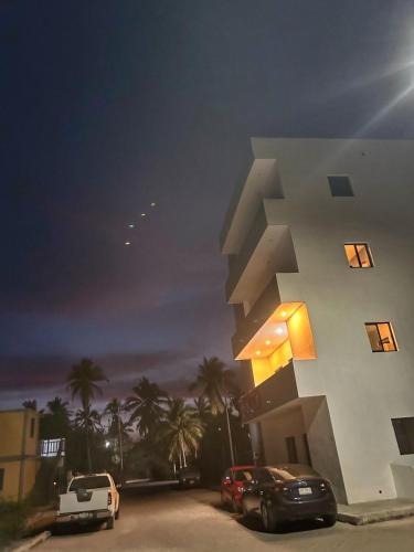 a building with cars parked in a parking lot at night at Tritón Apartment, ground floor and pool in Barra de Navidad