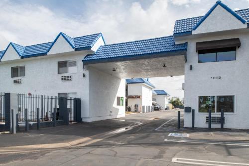 a white building with blue roofs on a street at beach inn motel in Huntington Beach