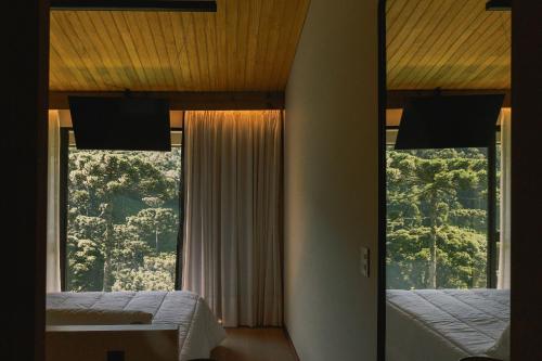a bedroom with two beds and a large window at Elegante bangalô de campo 5 - Taquaras Huts in Rancho Queimado
