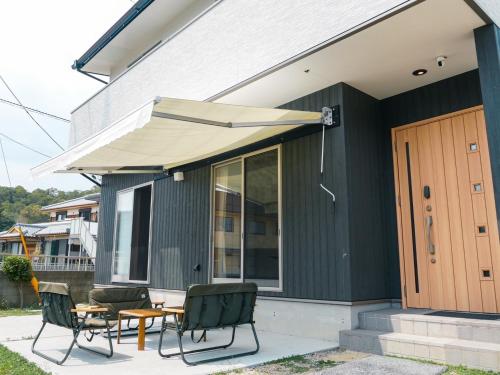a patio with a table and chairs and an umbrella at Vacation House YOKOMBO ANNEX in Naoshima