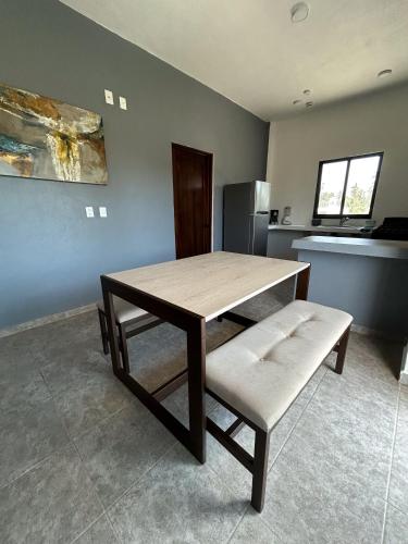 a table and a bench in a kitchen with a refrigerator at Tritón Apartment, ground floor and pool in Barra de Navidad