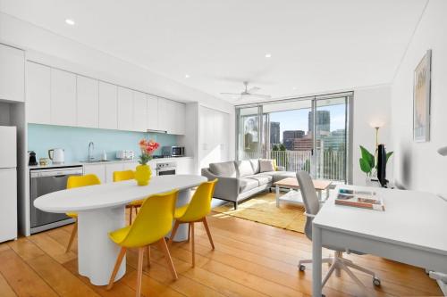 a kitchen and living room with a table and yellow chairs at Central luminous 2 beds with balcony & aircon in Sydney