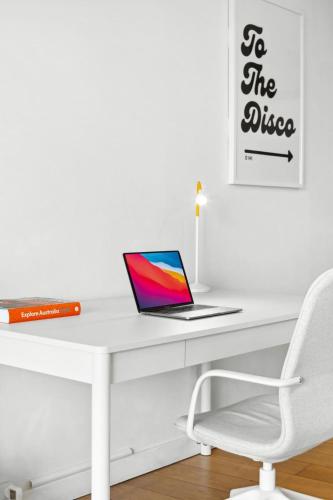 a laptop computer sitting on a white desk with a chair at Central luminous 2 beds with balcony & aircon in Sydney