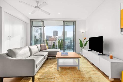 a living room with a couch and a tv at Central luminous 2 beds with balcony & aircon in Sydney