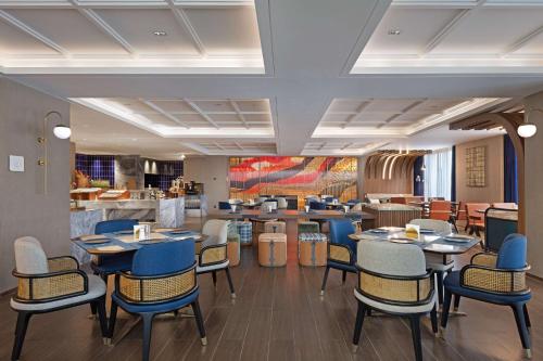 a restaurant with tables and chairs and a counter at Hilton Garden Inn Leshan Shizhong in Leshan
