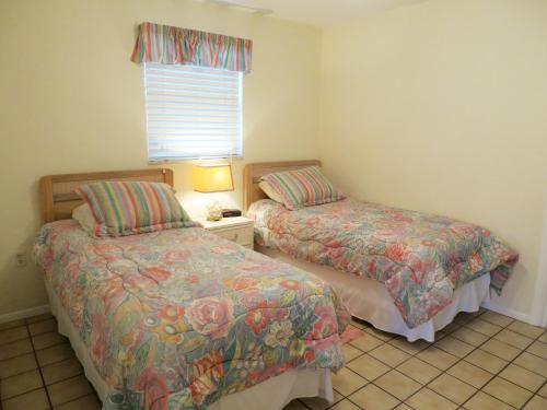 a bedroom with two beds and a lamp and a window at Sand Dollar Beach Side Villa in Holmes Beach
