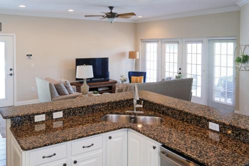 a kitchen with a sink and a living room at Hibiscus Hideaway Condo Walk To Historic Bridge St in Bradenton Beach