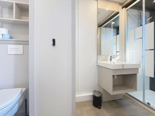 une salle de bain blanche avec un lavabo et des toilettes dans l'établissement Chalet de Standing avec Piscine Chauffée, à 300m de la Plage - 6 Couchages, WiFi Gratuit - FR-1-361-474, à Jullouville