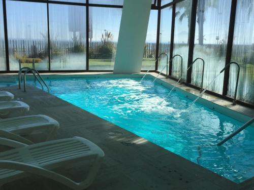 Una gran piscina con sillas en un edificio. en Jardín Del Mar - Casino-Playa, en Coquimbo