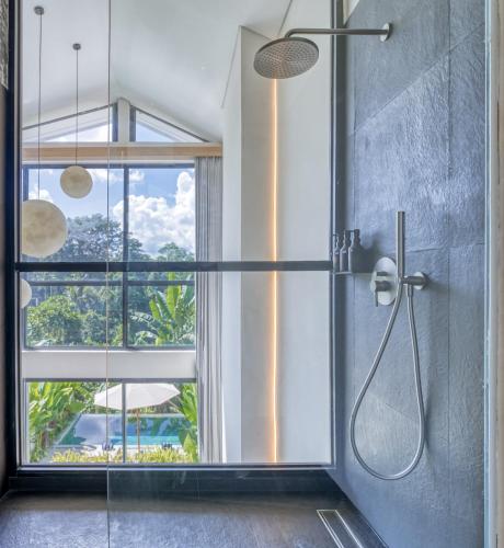 a bathroom with a shower with a large window at Loyo Villas in Tegalalang