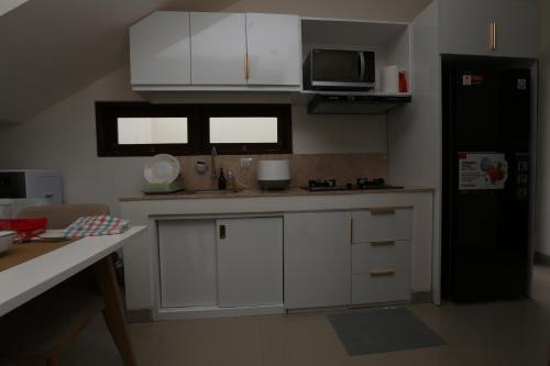 een keuken met witte kasten en een zwarte koelkast bij Rivera Seminyak 2 in Seminyak