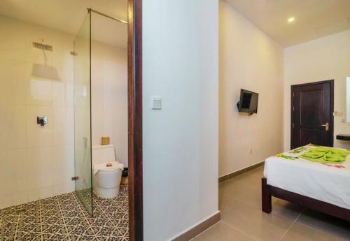 a bedroom with a bed and a shower and a toilet at Angkor Home 27 in Phumĭ Réach Born