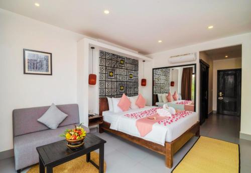 a bedroom with a large bed and a couch at Angkor Home 27 in Phumĭ Réach Born