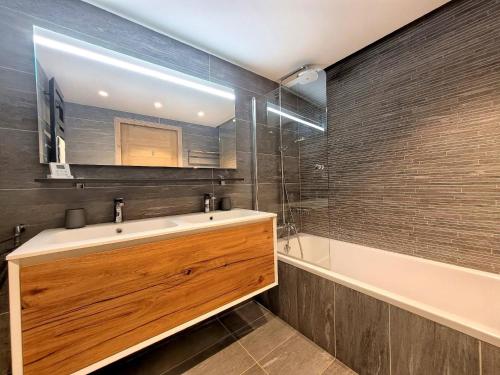 une salle de bain avec un lavabo, un miroir et une baignoire dans l'établissement Appartement spacieux au centre des Gets, 8 pers, 100m², accès direct pistes - FR-1-598-188, aux Gets