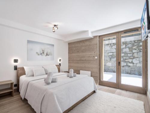 ein weißes Schlafzimmer mit einem großen Bett und einem Fenster in der Unterkunft Appartement neuf proche des pistes avec parking - FR-1-570-67 in Praranger