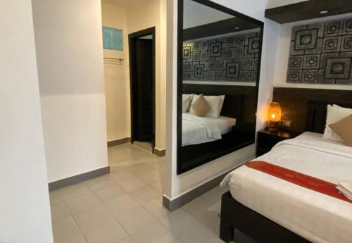 a bedroom with two beds and a large mirror at Angkor Home 27 in Phumĭ Réach Born