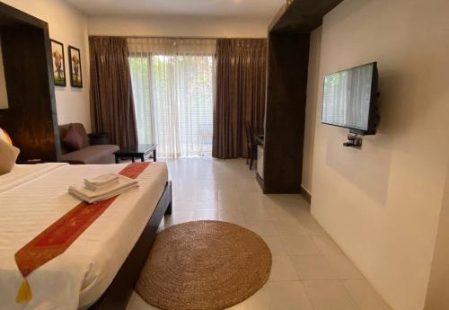a hotel room with a bed and a television at Angkor Home 27 in Phumĭ Réach Born