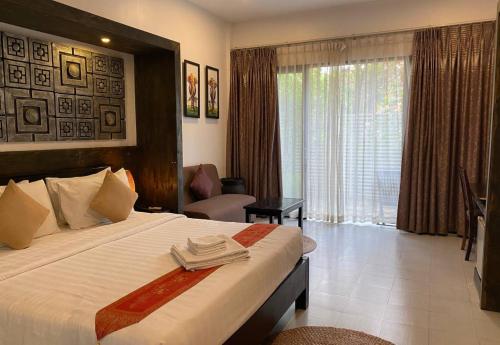 a hotel room with a bed and a large window at Angkor Home 27 in Phumĭ Réach Born