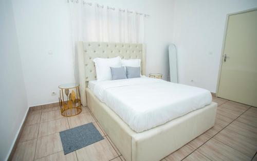 a white bedroom with a large white bed with pillows at Appartement Moderne & Confortable Proche Aéroport Léon-Mba, Libreville in Libreville